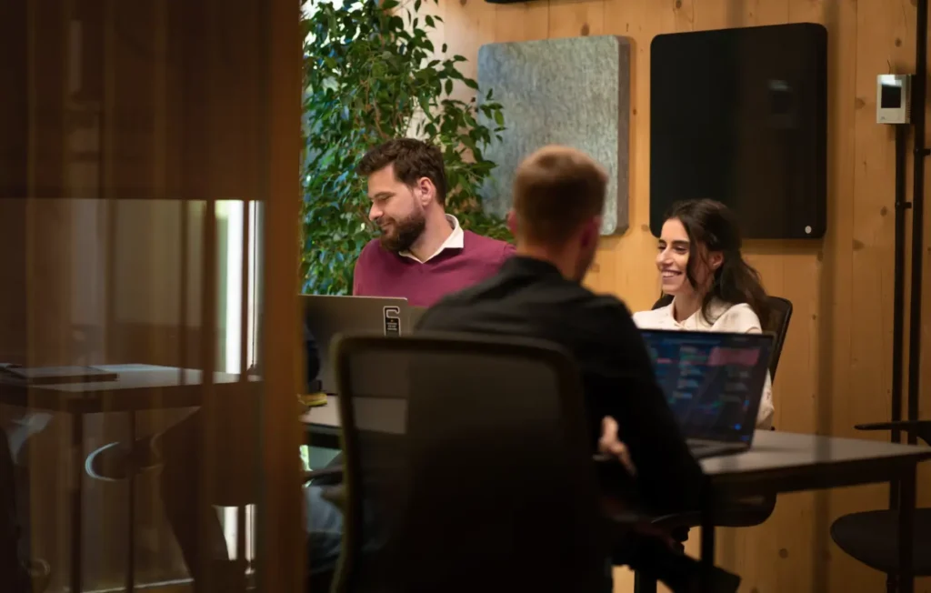 three people in an office sitting and working on computers